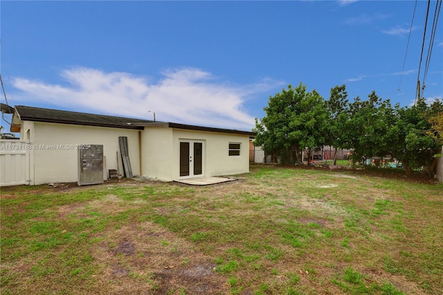 back of property with french doors and a lawn