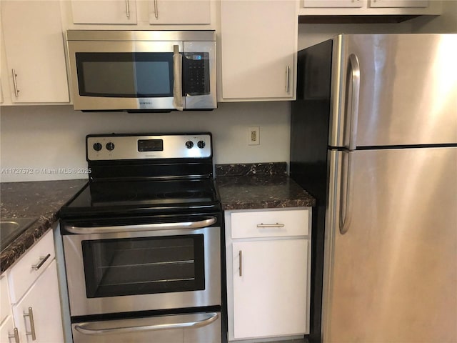 kitchen featuring stainless steel appliances, white cabinets, and dark stone counters