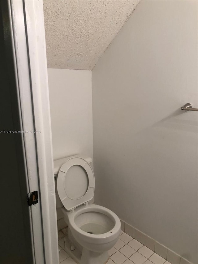 bathroom with tile patterned flooring, vaulted ceiling, a textured ceiling, and toilet