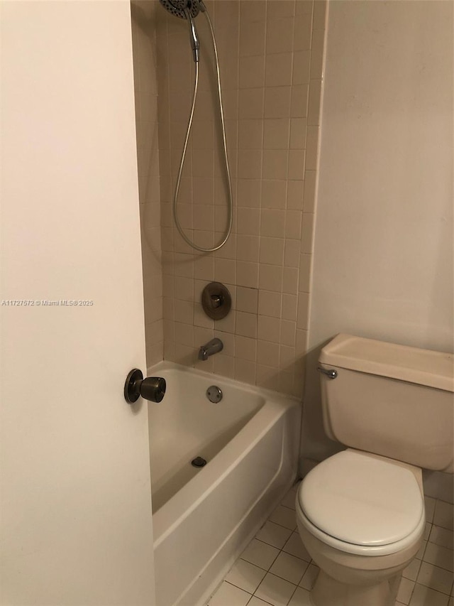 bathroom featuring toilet, tiled shower / bath combo, and tile patterned flooring