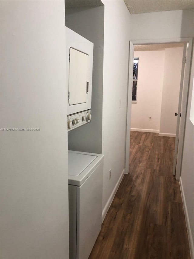 clothes washing area featuring stacked washer and clothes dryer, dark hardwood / wood-style floors, and a textured ceiling