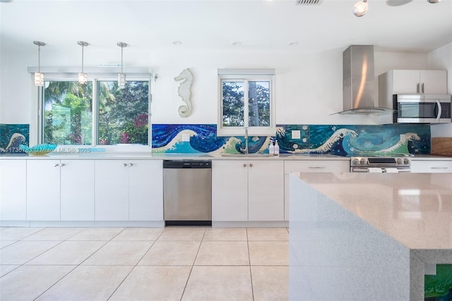 kitchen with white cabinetry, a healthy amount of sunlight, appliances with stainless steel finishes, and wall chimney range hood