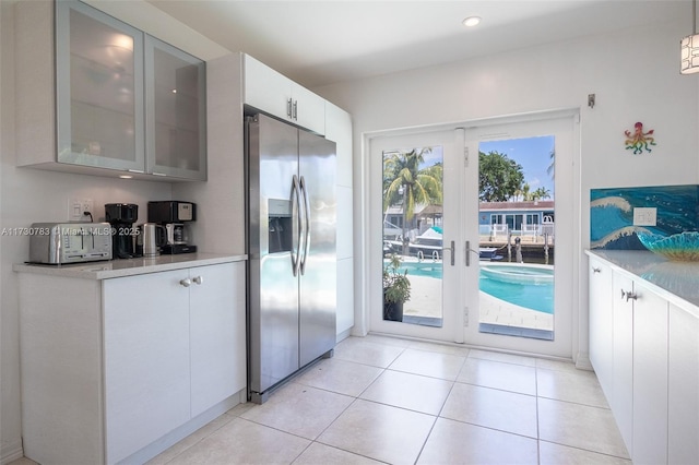 kitchen featuring stainless steel refrigerator with ice dispenser, light tile patterned floors, french doors, and white cabinets