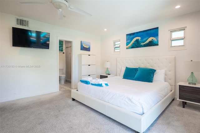 carpeted bedroom with multiple windows, ceiling fan, and ensuite bath