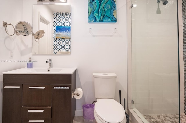 bathroom with tiled shower, vanity, and toilet