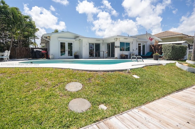 back of house with a fenced in pool, a yard, a patio area, and french doors