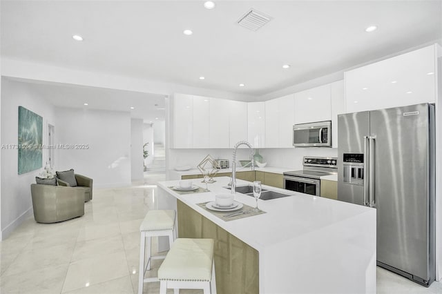 kitchen featuring sink, a breakfast bar area, light tile patterned floors, appliances with stainless steel finishes, and white cabinets