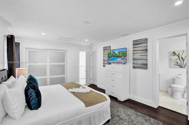 bedroom with ensuite bathroom and dark wood-type flooring