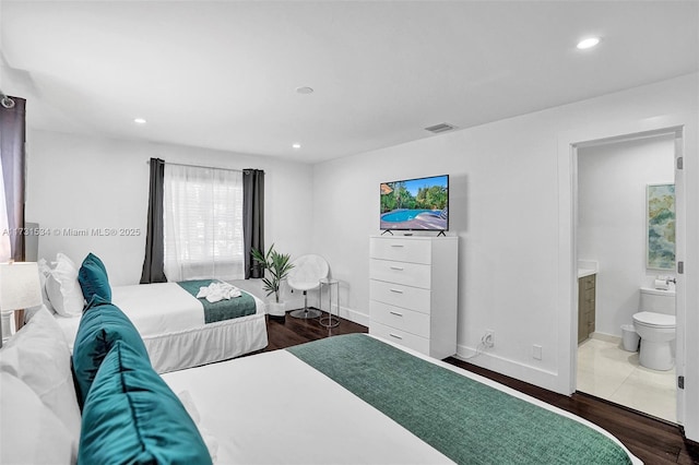 bedroom featuring connected bathroom and dark hardwood / wood-style floors