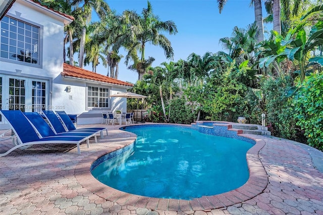 view of pool with french doors, an in ground hot tub, and a patio