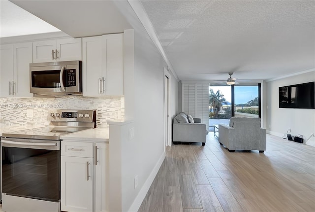 kitchen with tasteful backsplash, white cabinetry, appliances with stainless steel finishes, and a textured ceiling