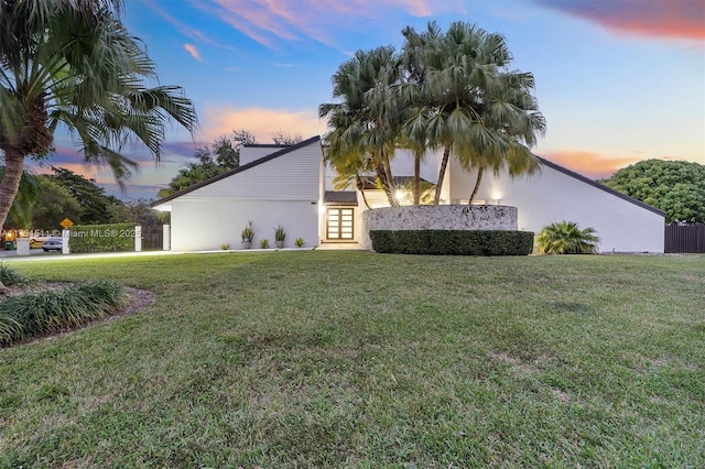 property exterior at dusk with a lawn