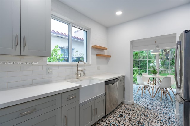 kitchen featuring stainless steel appliances, gray cabinets, sink, and backsplash