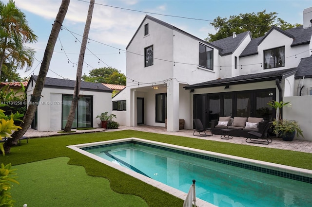 rear view of house featuring an outdoor living space, a patio, and a lawn