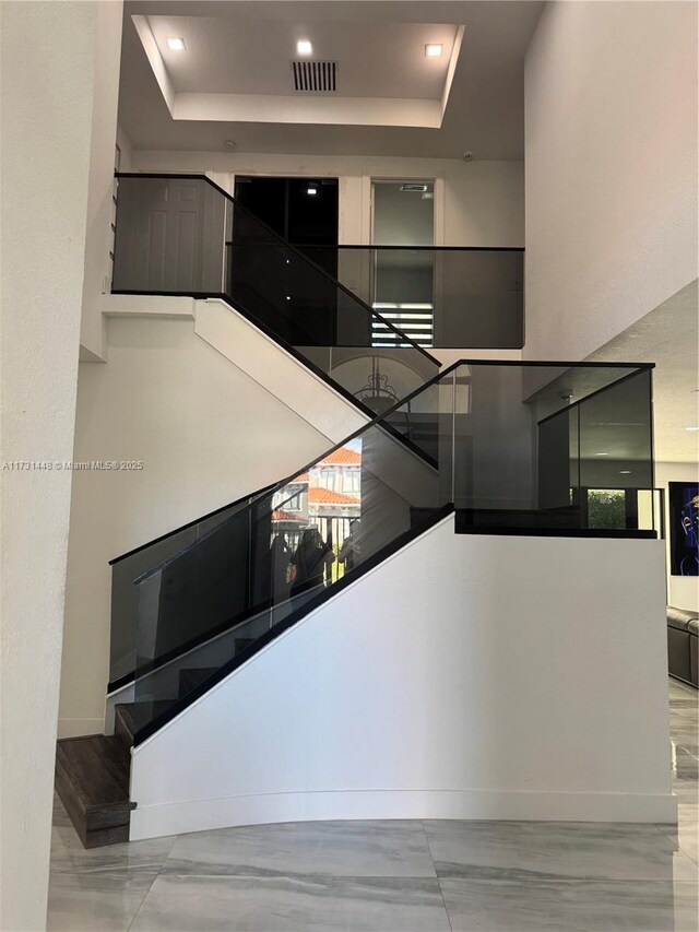 staircase featuring a towering ceiling and a tray ceiling