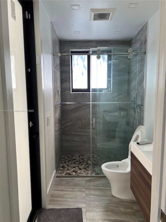 bathroom featuring a shower with door, vanity, and toilet