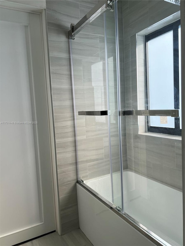 bathroom with a healthy amount of sunlight and shower / bath combination with glass door