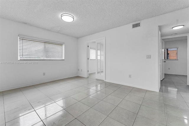 spare room featuring light tile patterned floors and a textured ceiling