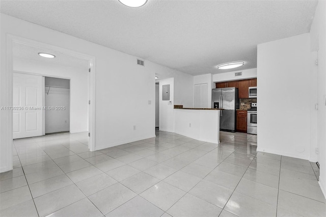 unfurnished living room featuring electric panel, a textured ceiling, and light tile patterned flooring