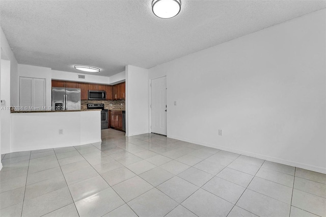 unfurnished living room with light tile patterned flooring and a textured ceiling