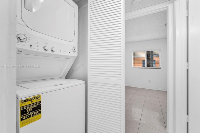 laundry area with stacked washer / dryer, light tile patterned flooring, and a textured ceiling