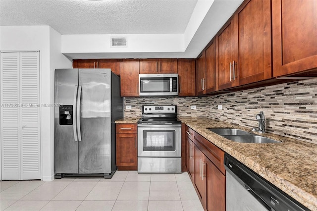 kitchen featuring appliances with stainless steel finishes, light stone countertops, sink, and decorative backsplash