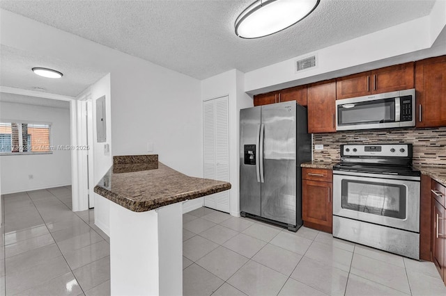 kitchen with tasteful backsplash, stainless steel appliances, kitchen peninsula, and light tile patterned flooring