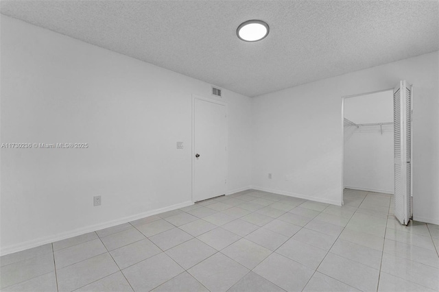 unfurnished bedroom with a walk in closet, a textured ceiling, and a closet