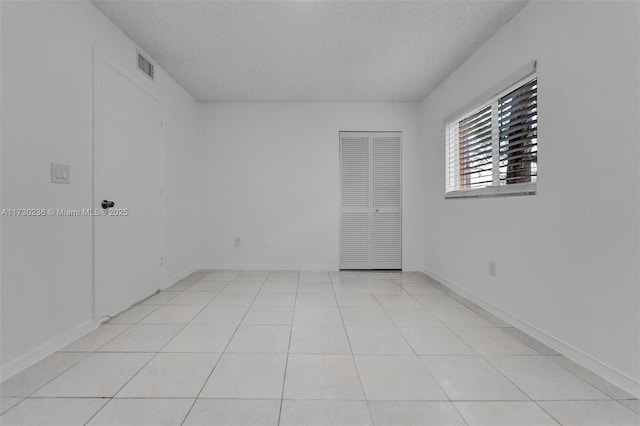 tiled spare room featuring a textured ceiling