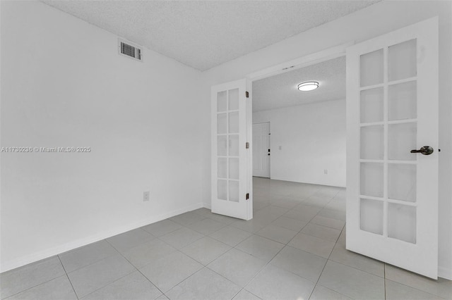 tiled spare room featuring built in shelves, a textured ceiling, and french doors