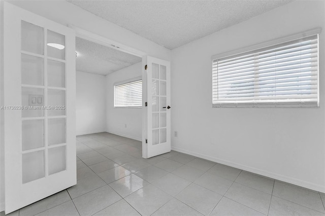 tiled empty room with french doors and a textured ceiling