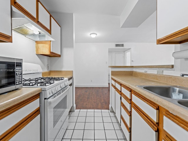 15315 SW 106th Ter Unit 423, Miami, FL 33196 - kitchen featuring white gas range oven, custom exhaust hood, stainless steel microwave, light countertops, and light tile patterned floors