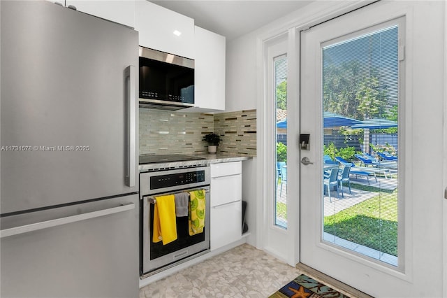 kitchen featuring backsplash, a healthy amount of sunlight, stainless steel appliances, and white cabinets