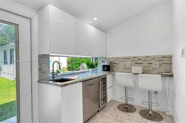 kitchen with tasteful backsplash, dishwasher, sink, and white cabinets