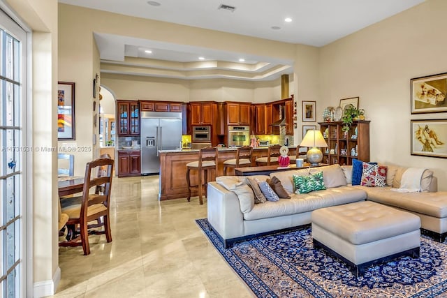 living room featuring a raised ceiling and a high ceiling