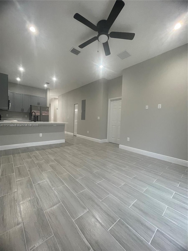 unfurnished living room with sink, electric panel, and ceiling fan