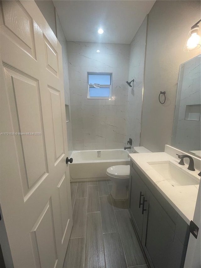 full bathroom with vanity, tiled shower / bath combo, and toilet