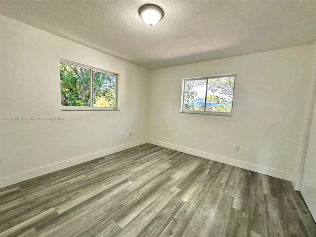 unfurnished room with hardwood / wood-style flooring and a textured ceiling