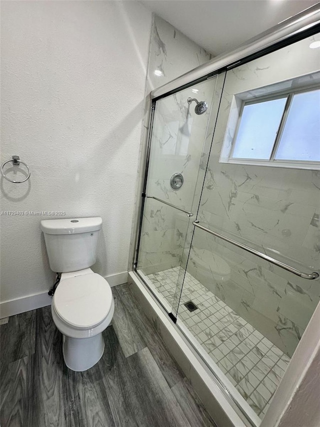 bathroom with wood-type flooring, toilet, and a shower with shower door