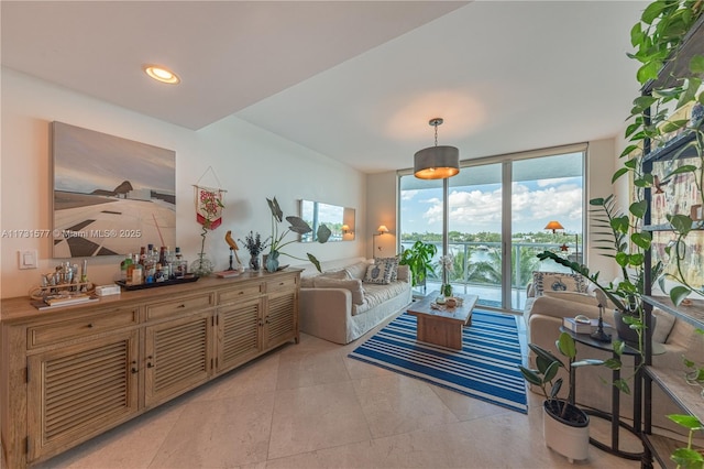 living room featuring light tile patterned floors, recessed lighting, a water view, and expansive windows