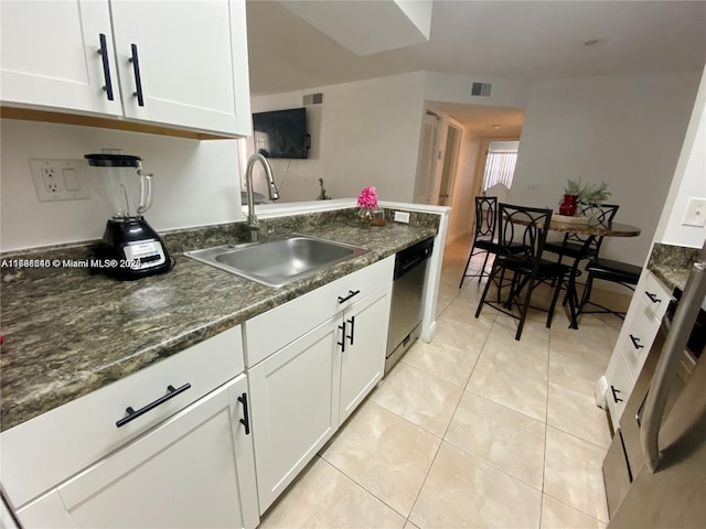 kitchen with sink, white cabinetry, dark stone countertops, light tile patterned floors, and stainless steel dishwasher