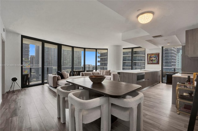 dining space featuring sink, a wall of windows, and light hardwood / wood-style floors