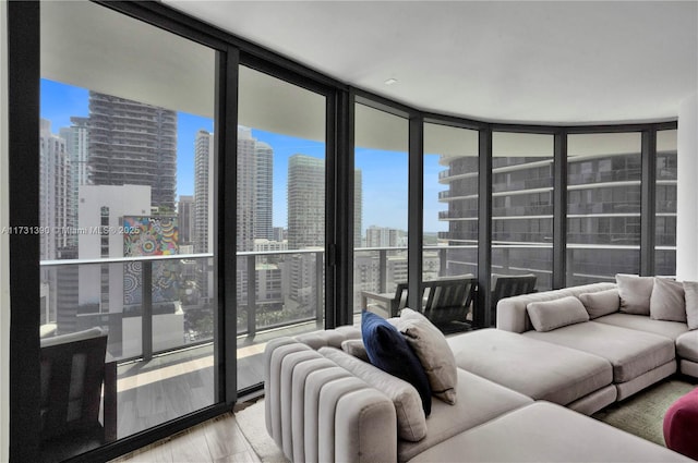 living room with light hardwood / wood-style floors, floor to ceiling windows, and a healthy amount of sunlight