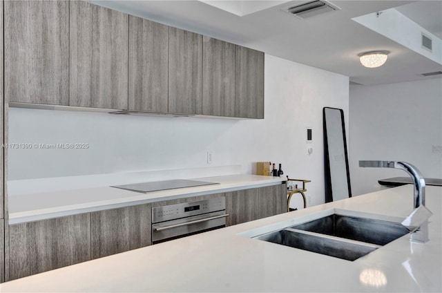 kitchen featuring black electric stovetop, sink, and stainless steel oven