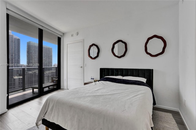 bedroom with light hardwood / wood-style floors and floor to ceiling windows