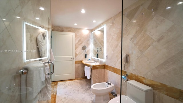 bathroom with a bidet, vanity, toilet, and tile walls