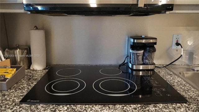 room details with black electric cooktop and dark stone counters