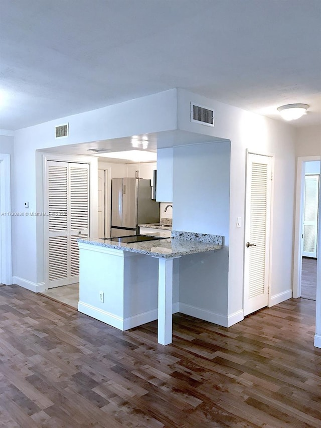 kitchen featuring dark hardwood / wood-style floors, sink, stainless steel fridge, white cabinets, and kitchen peninsula