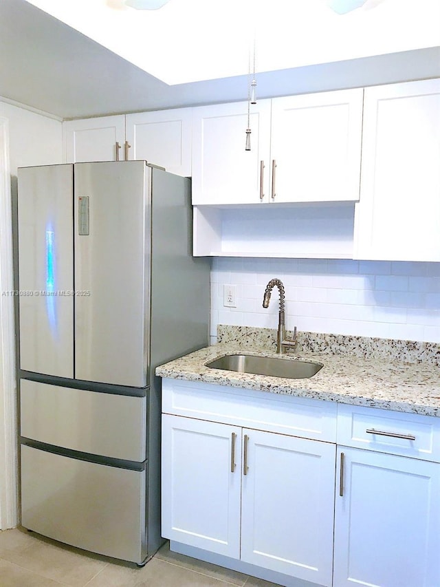 kitchen featuring white cabinetry, sink, decorative backsplash, and stainless steel refrigerator