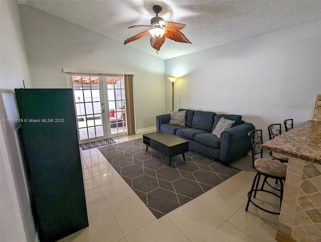 tiled living room featuring lofted ceiling, ceiling fan, french doors, and a textured ceiling